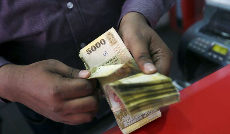 A man counts Sri Lankan rupees at a money exchange counter in Colombo